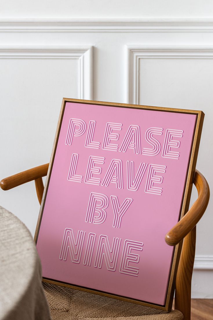 a pink sign sitting on top of a wooden chair next to a white tablecloth