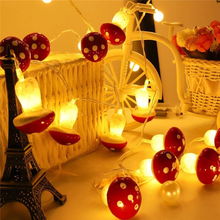 some lights that are sitting on a table next to a bike and basket with flowers in it