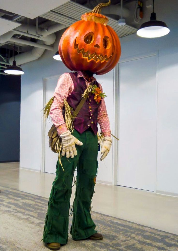 a scarecrow with a large pumpkin on his head and hands in the shape of a jack - o'- lantern