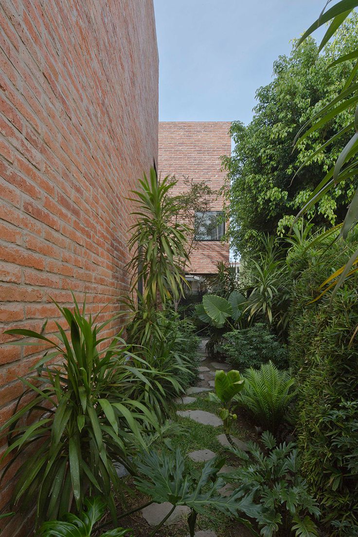 a brick building with lots of trees and plants in it's side walk way