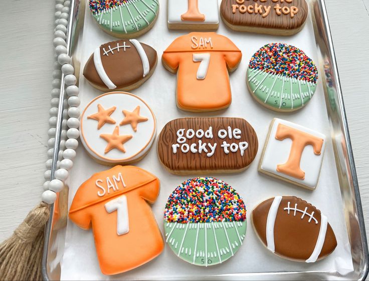 decorated cookies in the shape of footballs and numbers on a tray with tassels