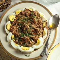 an egg dish with meat and eggs in it on a plate next to silverware