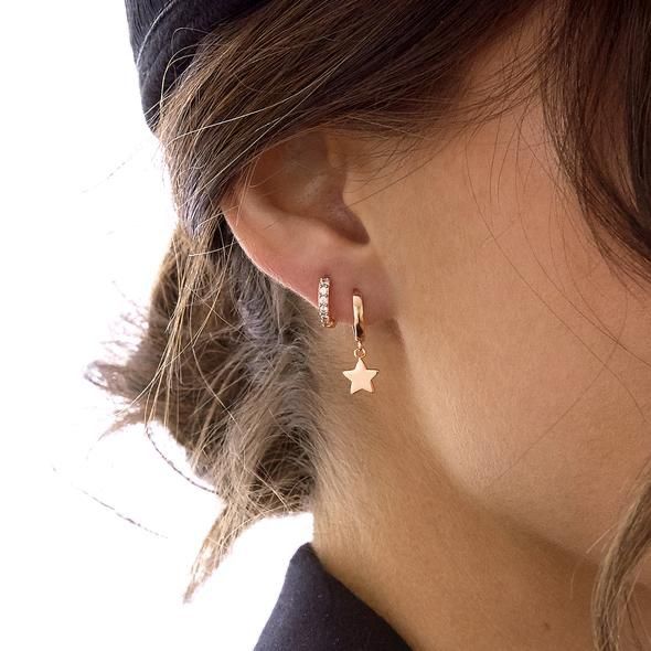 a close up of a woman's ear wearing gold earrings with stars on them