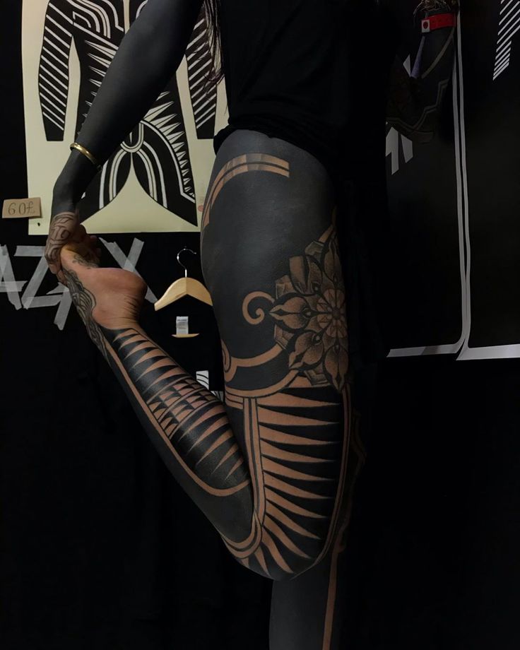 a woman with tattoos on her legs and leggings is holding something in her hand