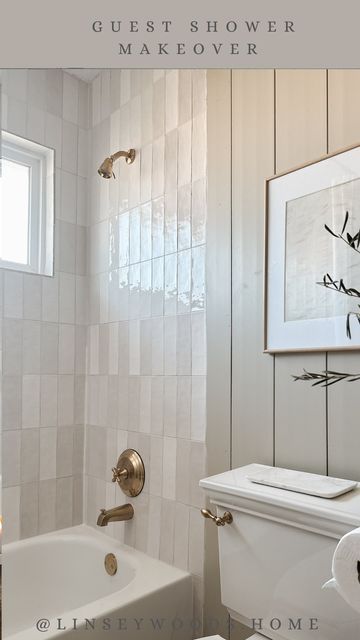 a white toilet sitting next to a bath tub in a bathroom under a framed picture