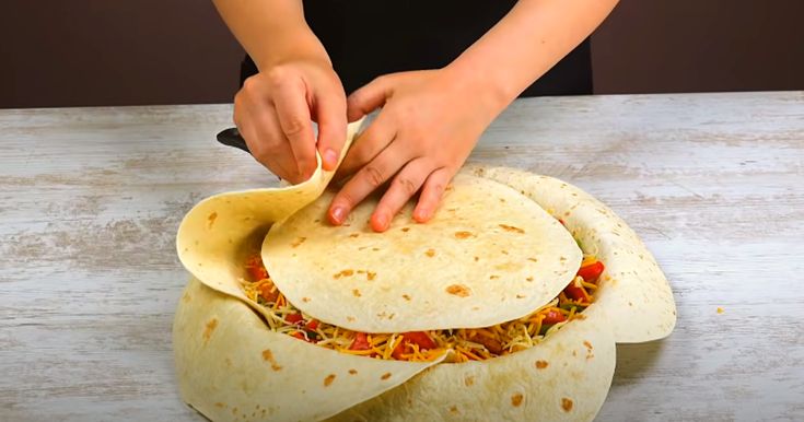 a woman is making tortilla wraps on a counter top with her hands in the wrapper