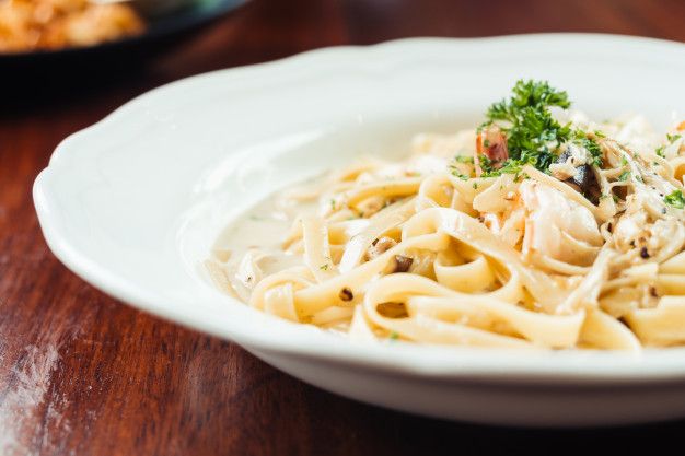 a white bowl filled with pasta on top of a wooden table