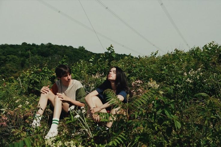 two people sitting on the ground in tall grass