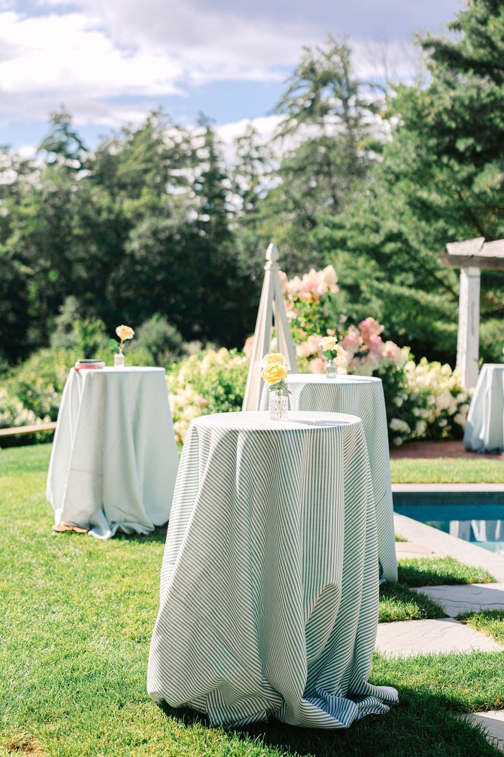 an outdoor setting with tables and chairs covered in white tablecloths next to a pool