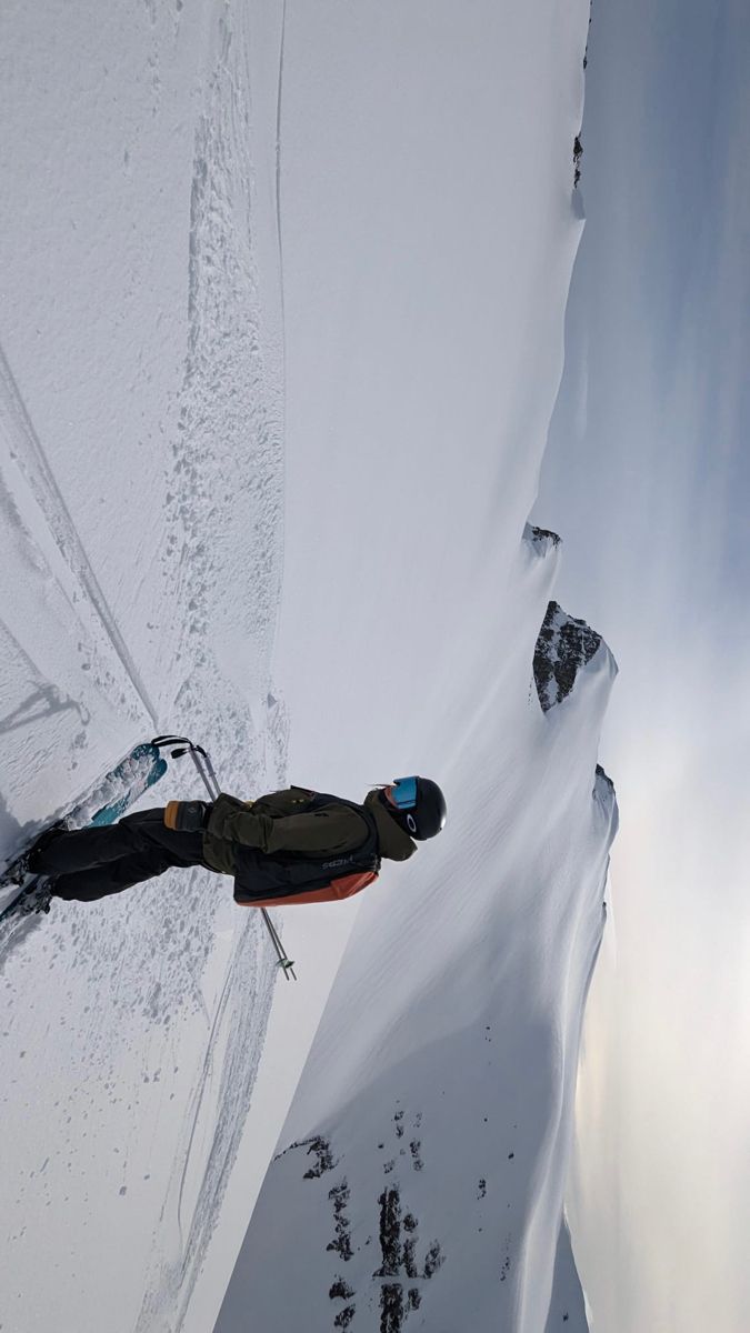 a man riding skis down the side of a snow covered slope next to a mountain