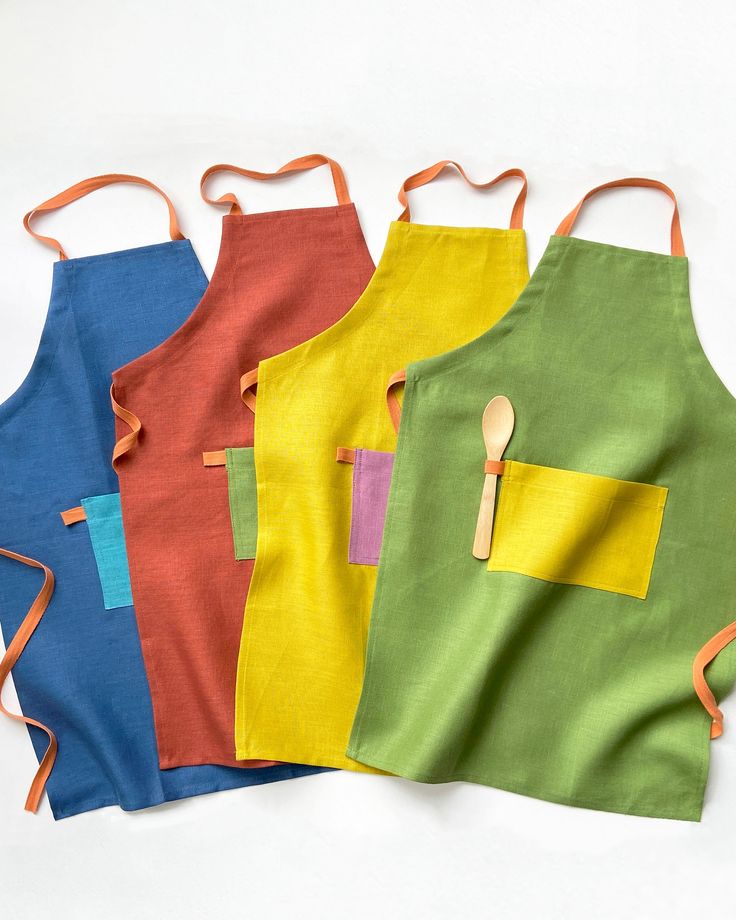 three aprons with wooden spoons on them