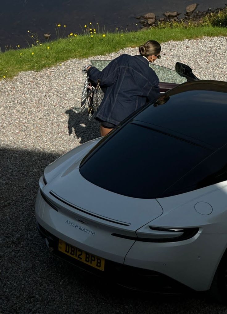 a man sitting in the back of a white car next to a body of water