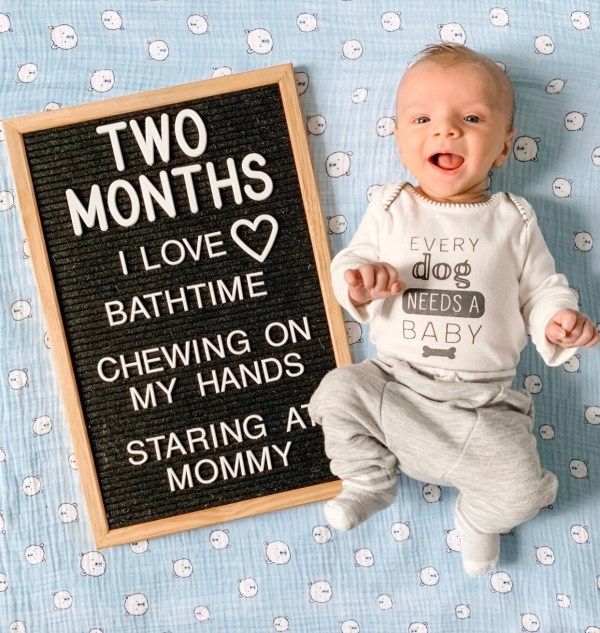 a baby laying next to a chalkboard with two months written on it