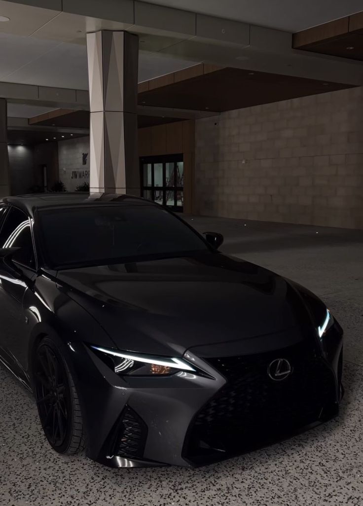 a black sports car parked in a parking garage next to a tall building with columns