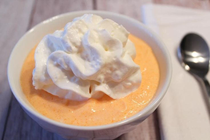 a bowl filled with whipped cream on top of a wooden table