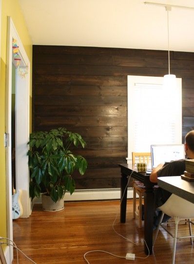 a man sitting at a desk in front of a laptop computer on top of a wooden floor