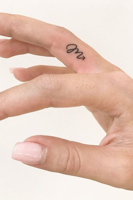 a person's hand with a small tattoo on the middle finger that says love