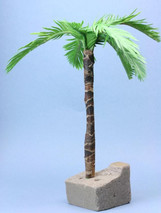 a small palm tree sitting on top of a cement block in front of a blue background