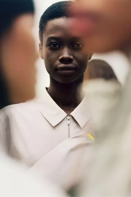 a woman in a white shirt is looking at the camera while another person looks on