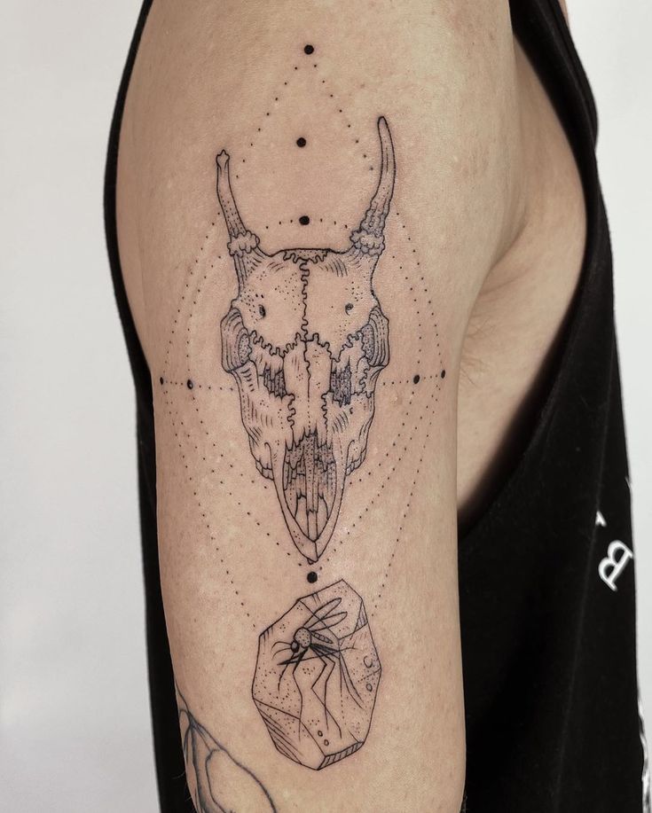 a man's arm with tattoos on it and an animal skull in the middle