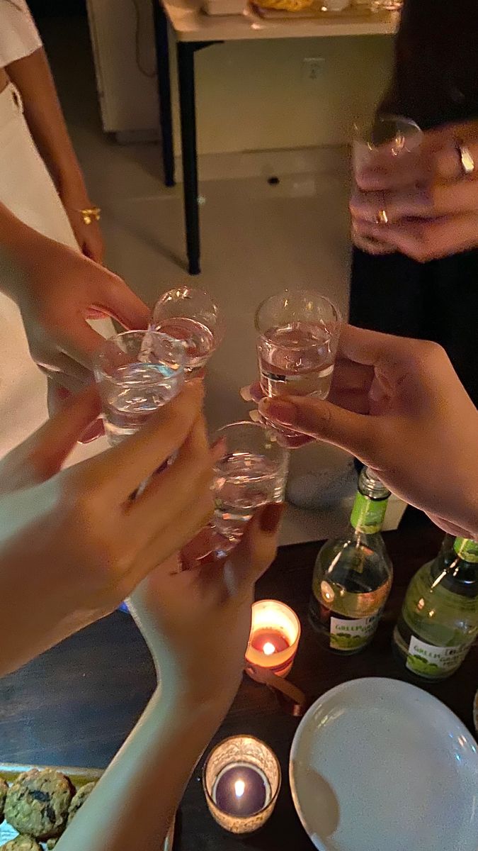 several people toasting with wine glasses in front of candles and plates on a table