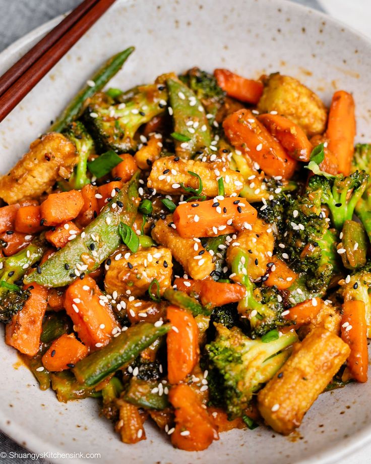 a white plate topped with broccoli and carrots next to chopsticks