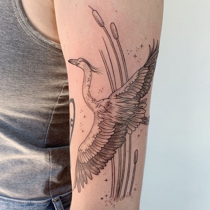 a woman's arm with a bird tattoo on it