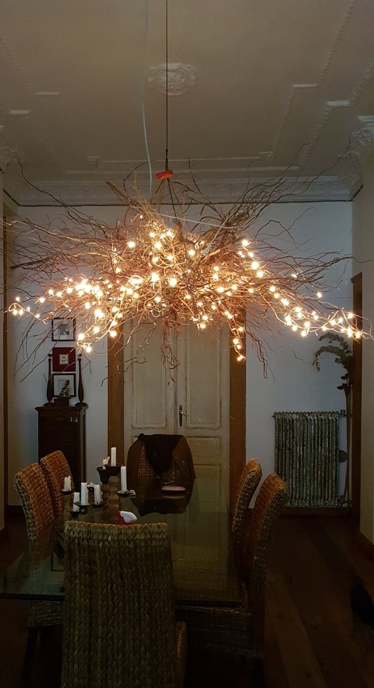 a chandelier hanging from the ceiling in a dining room filled with furniture and decor