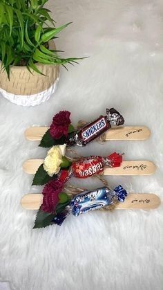 three wooden skis with candy bars and flowers in them on a white furnishing