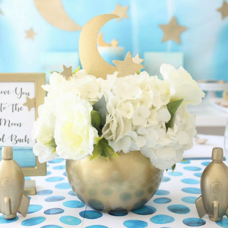 there is a vase with white flowers in it and two little birds on the table