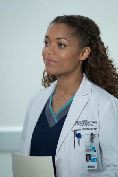 a woman in a white lab coat holding a clipboard and looking off into the distance