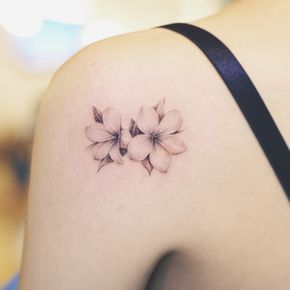 a woman's back shoulder with three flowers on the left side of her arm