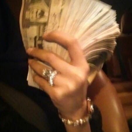 a close up of a person holding money in their hand and wearing rings on her fingers