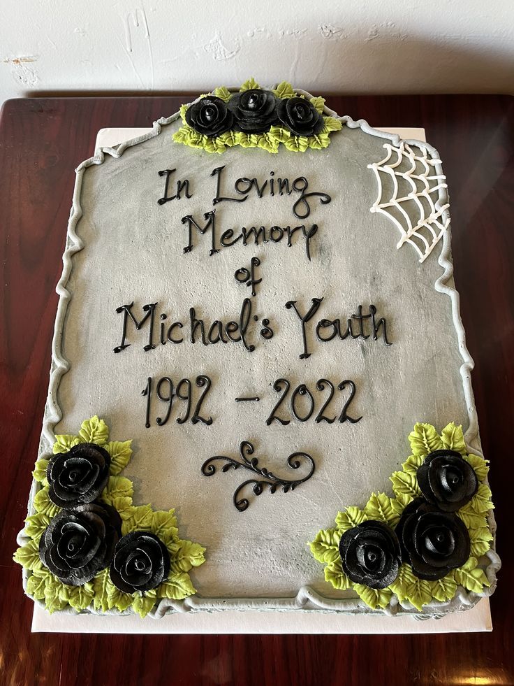 a sheet cake decorated with black roses and writing on the side that says in loving memory of michael's youth