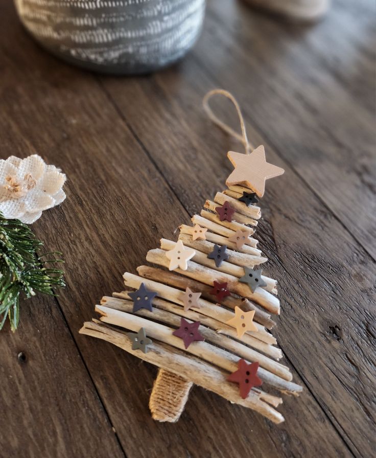 a christmas tree made out of clothes pegs on a wooden table next to a potted plant