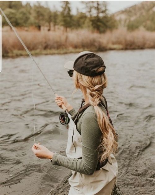 a woman standing in the water holding a fishing line