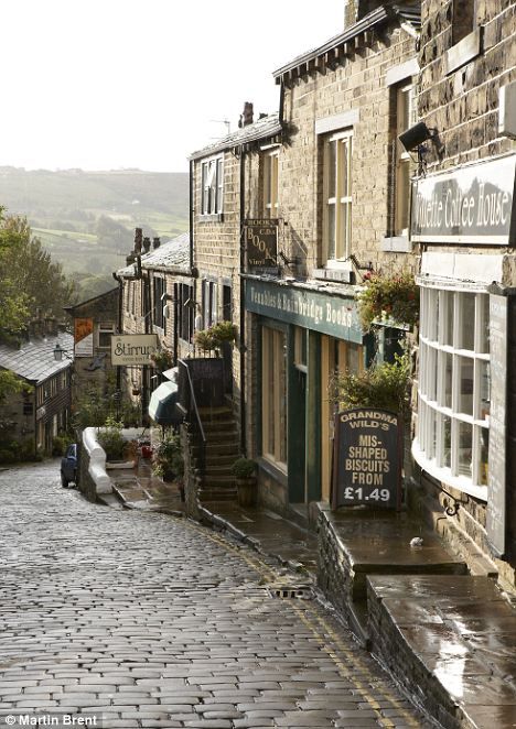 a cobblestone street with shops and people walking down it