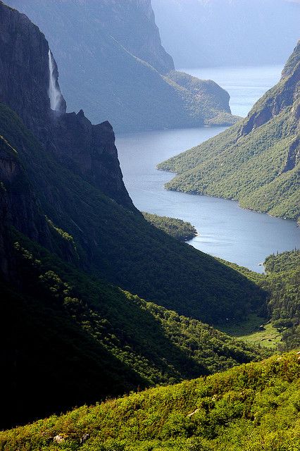 a view of mountains, water and grass from the top of a hill