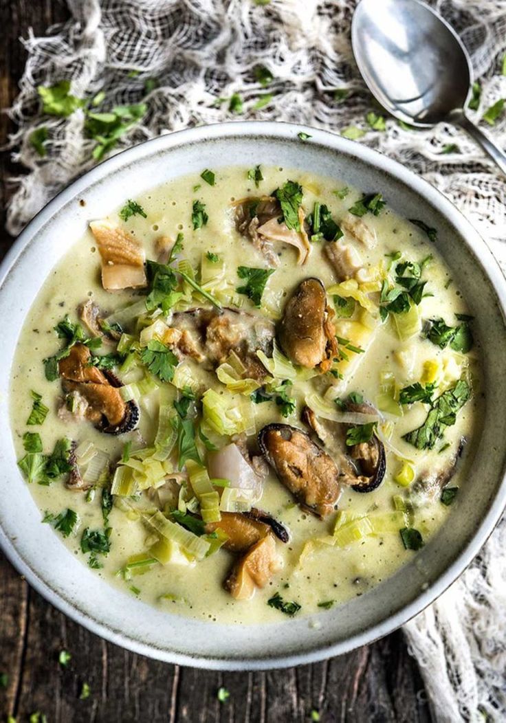 a white bowl filled with soup on top of a wooden table next to a spoon