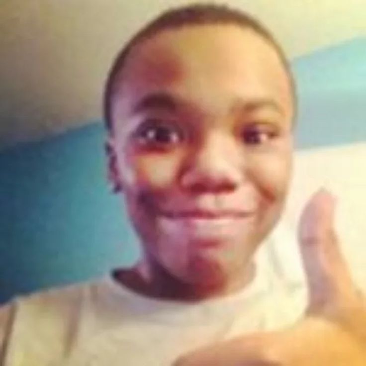 a young man making the peace sign with his hand and smiling at the camera while wearing a white t - shirt