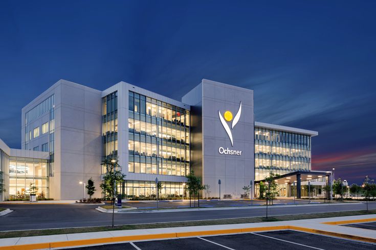 an office building lit up at night with the lights on and parking lot in front