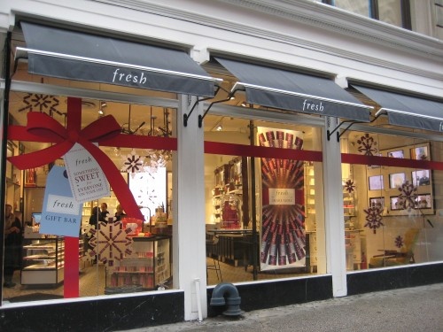 a store front with christmas decorations on it's windows and red bows hanging from the window