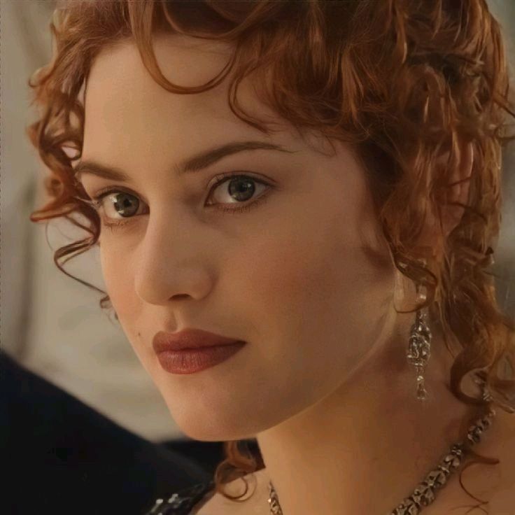 a close up of a woman with red hair and jewelry on her neck, looking at the camera