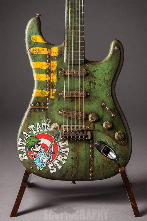 an old green guitar sitting on top of a wooden stand