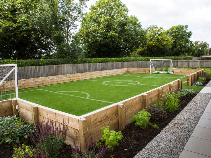 an outdoor soccer field with artificial turf and wooden fenced in areas surrounding the yard