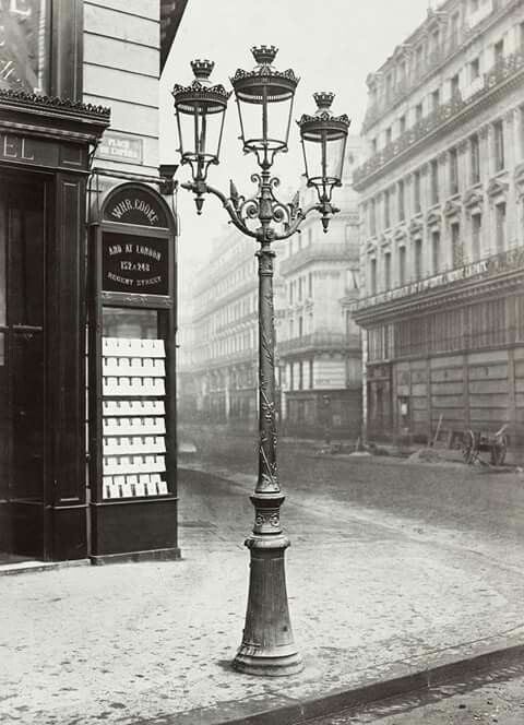 an old fashioned lamp post in the middle of a street