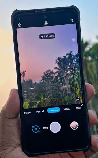 someone is holding up their cell phone to take a photo with palm trees in the background