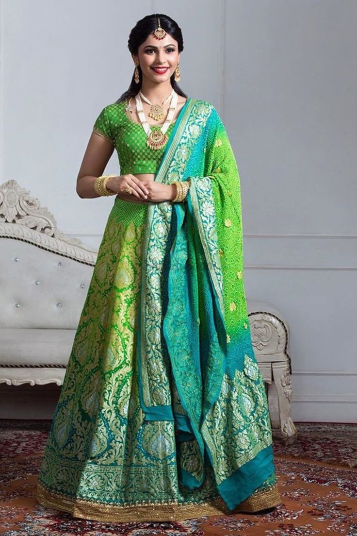 a woman in a green and blue lehenga is posing for the camera with her hands on her hips