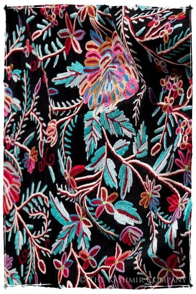 an embroidered fabric with colorful flowers and leaves on black, pink, blue, green, red