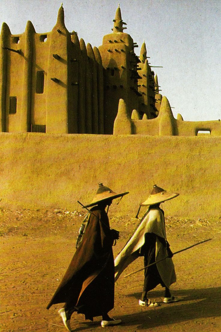 two people walking in front of a sand castle with their backs turned to the camera